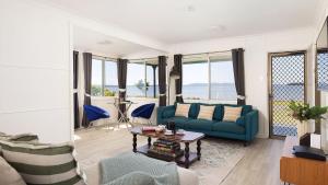a living room with a blue couch and a table at Waterfront Cottage in New South Wales  +24 photos