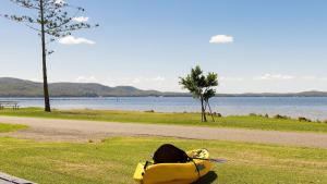 a yellow bag sitting on the grass near a body of water at Waterfront Cottage in New South Wales 