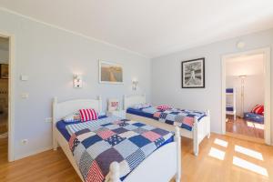 two beds in a bedroom with white walls and wood floors at Ferienhaus Krause in Trent