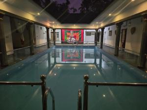 una piscina en un edificio con una pintura en la pared en Kudajadri Heritage Pool Homestay Kothamangalam, en Kotamangalam