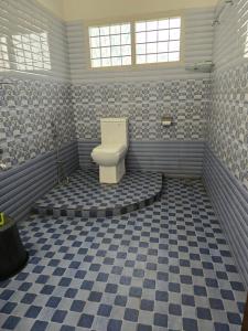 Baño con aseo en un suelo a cuadros en Kudajadri Heritage Pool Homestay Kothamangalam, en Kotamangalam