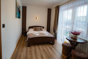 a bedroom with a bed and a table and a window at Noclegi u Masnych in Witów