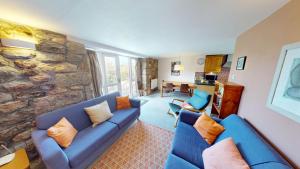 Saddle Cottage في بينزانس: غرفة معيشة مع أريكة زرقاء وجدار حجري