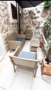 a patio with wicker chairs and tables and a stone wall at Secret House Andrea in Primošten