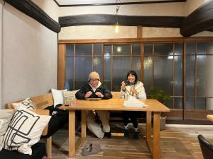 a man and woman sitting at a wooden table at 泊まれるカフェやわらかそう in Koka