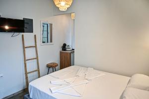 a room with a bed with white sheets and a ladder at Ikaria Studios in Agios Kirykos
