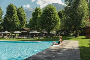 a woman is standing in the water by a swimming pool at Ferien & Wellnesshotel Windschar in Brunico