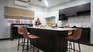 eine Küche mit einer schwarz-weißen Theke und Hockern in der Unterkunft Luxury 6BHK Villa with Private Pool in Pattaya by - OzyStays in Nong Prue