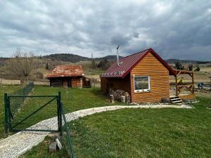 a wooden cabin with a red roof on a field at Tiny House at Sedliacky Dvor - Brezno in Brezno