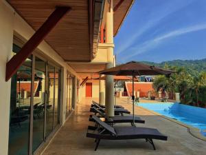 a row of chairs with umbrellas next to a pool at Kata Sea Cloud Villa半山海景独栋别墅 in Ban Kata
