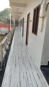 a corridor of a white building with a wooden floor at Geetasheel Palace in Naimishāranya