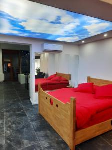 1 dormitorio con 2 camas con sábanas rojas y techo con techo pintado. en Nuit Express à Love Suite L'Origin'El d'Ornans, en Ornans
