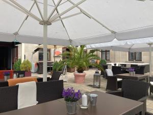 a patio with tables and chairs under a white umbrella at Hotel Uckermark in Prenzlau
