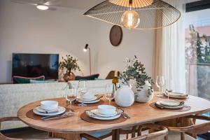 a wooden table with plates and glasses and a chandelier at Apartment in the heart of Javea - By Welcomely in Jávea