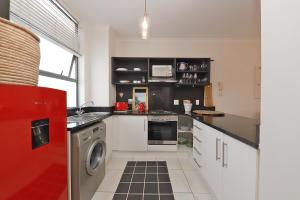 a kitchen with white cabinets and a red refrigerator at Muizenberg Apartment in Muizenberg