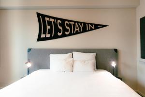 a bedroom with a bed with a sign that reads let s stay in at The Social Hub The Hague in The Hague