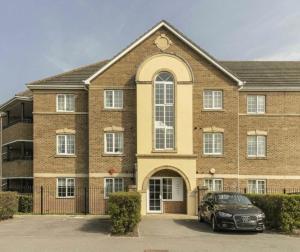 a large brick building with a car parked in front at Spacious 2-Bed Family Flat in Wimbledon Near Tube in London