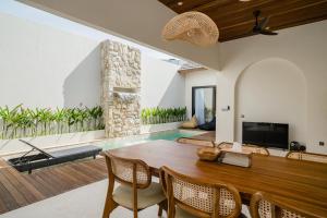 a living room with a wooden table and a television at La Tropical Uluwatu, Bingin in Uluwatu