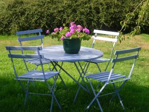 einen Tisch mit zwei Stühlen und eine Kanne Blumen drauf in der Unterkunft Quaint Holiday Home in Chimay with Garden in Plagneau