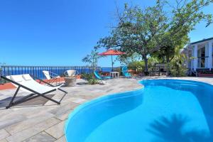 a swimming pool with a chair and an umbrella at Villa Vue-Belle in Saint-Paul