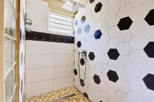 a bathroom with a shower with black and white tiles at Villa Vue-Belle in Saint-Paul