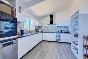 a large white kitchen with white cabinets and appliances at Villa Vue-Belle in Saint-Paul