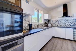 a kitchen with white cabinets and a large window at Villa Vue-Belle in Saint-Paul