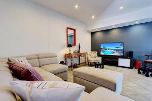 a living room with a couch and a flat screen tv at Villa Vue-Belle in Saint-Paul