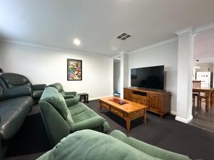 a living room with green couches and a flat screen tv at Busselton Broadwater Holiday Home in Busselton