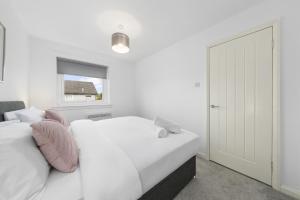 a white bedroom with two beds and a window at 1-Bed Home in Lanarkshire with Free Parking - Long Stays Available in Newarthill