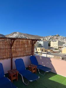 two blue chairs and a table on a roof at Aiantas in Ermoupoli