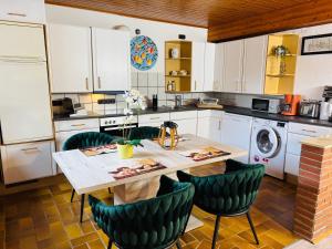 a kitchen with a wooden table and green chairs at Maja Ferienwohnung in Goddelsheim