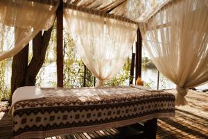 a bed on a deck with curtains and a river at Country SPA Village in Ciofliceni +99 photos