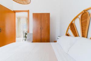 a bedroom with a white bed and a wooden cabinet at Casa Vacanze Irene - Salento Selection in Torre Lapillo +21 photos