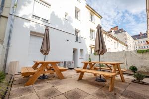 two picnic tables with umbrellas on a patio at Appartement Stylé pour 4 in Châlons-en-Champagne