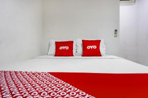 a bed with two red pillows with the word oxy at Hotel O Royani Residence in Jakarta