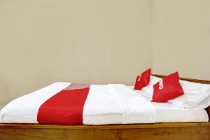 a red and white bed with red pillows on it at OYO 91261 Cita Suraya Homestay in Banyuwangi