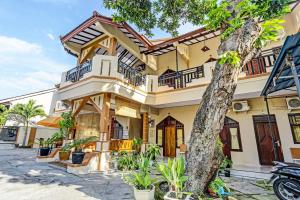 a house with a tree in front of it at OYO 91261 Cita Suraya Homestay in Banyuwangi
