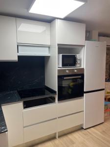 a white kitchen with a microwave and a stove at El Portalet in Montblanc