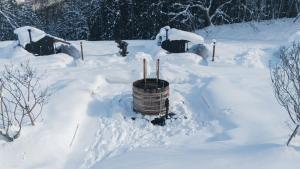 a snow covered yard with a barrel in the snow at Earthboat Hakuba in Hakuba