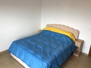 a bed with a blue comforter and a yellow blanket at Orizzonte Blu Holiday Home in Scalea