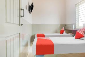 two beds in a room with red and white at OYO 91316 Hh Guest House Makassar in Makassar +18 photos