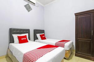 two beds in a room with red and white sheets at Hotel O Homestay Al Maidah in Sleman