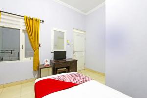 a white bedroom with a bed and a television at Hotel O Homestay Al Maidah in Sleman +22 photos