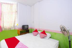 a bedroom with a bed with red and white pillows at Hotel O Kartika Guest House SyariahNearPantai Stres in Jodoh
