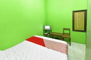 sypialnia z łóżkiem, krzesłem i biurkiem w obiekcie SPOT ON 91357 Hotel Mulyo w mieście Purwokerto