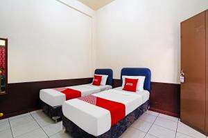 two beds with red pillows in a room at Hotel O Mutiara in Magelang +20 photos