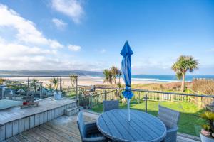 einen Tisch mit Sonnenschirm auf einer Terrasse mit Strand in der Unterkunft Beach View House - Self Catering Hayle, St Ives Bay Cornwall in Hayle