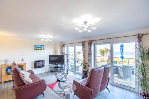 ein Wohnzimmer mit einem Sofa, Stühlen und einem TV in der Unterkunft Beach View House - Self Catering Hayle, St Ives Bay Cornwall in Hayle