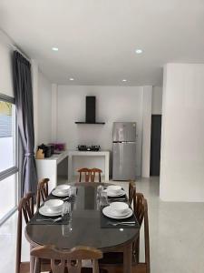 Home Phuket Andaman 3BR في Ban Klang: غرفة طعام مع طاولة مع كراسي ومطبخ
